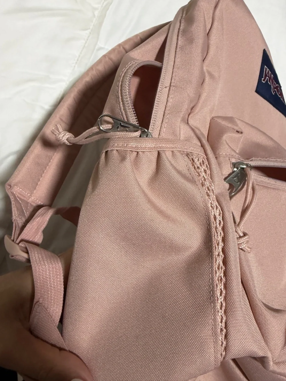 JanSport Cross Town backpack in a light pink color with a blue logo patch